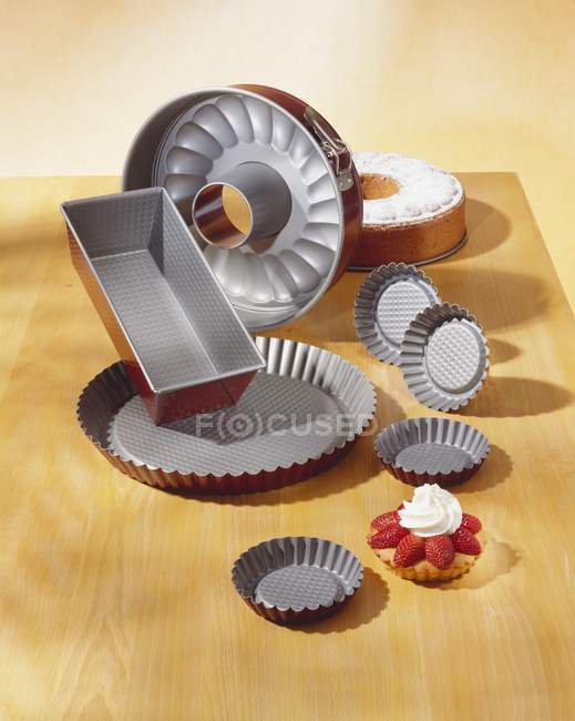 Elevated view of various baking tins with cakes on wooden surface — Stock Photo