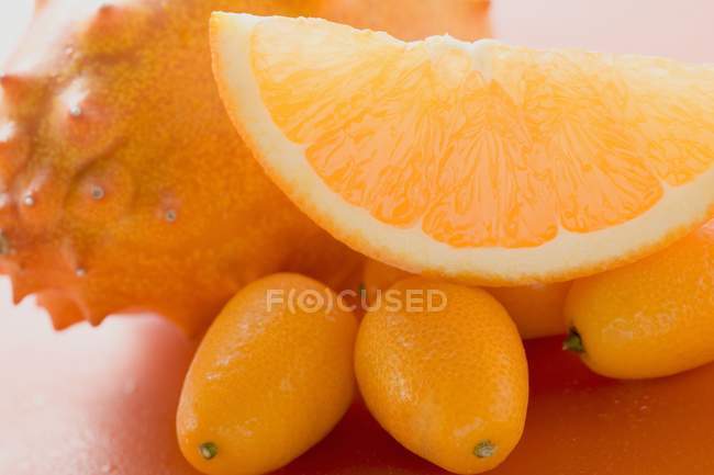 Kiwano, kumquats and wedge of orange — Stock Photo