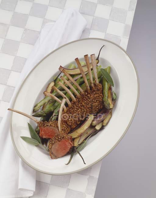 Lamb in herb crust on green asparagus — Stock Photo
