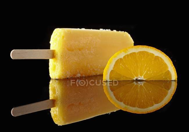 Closeup view of orange lolly and a slice of orange — Stock Photo