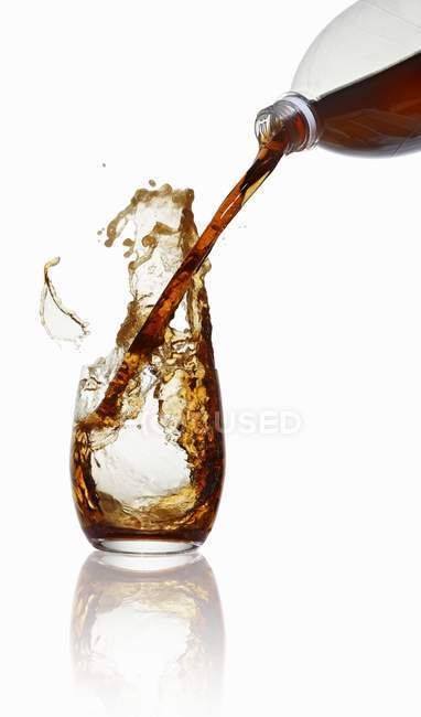 Вид крупным планом разливки колы из бутылки в стекло — стоковое фото