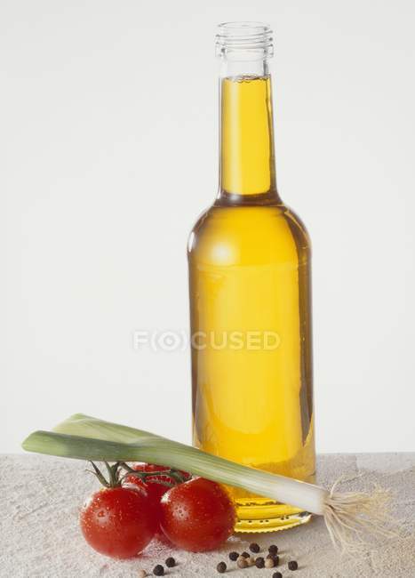 Vista de cerca de una botella de aceite con verduras - foto de stock