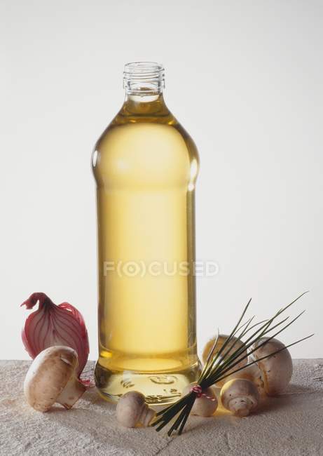 Vista de cerca de una botella de aceite con champiñones, mitad cebolla y cebollino - foto de stock