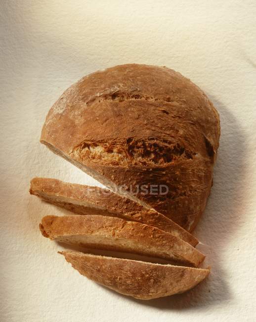 Loaf of bread, partly sliced — Stock Photo