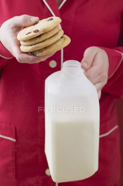 Крупним планом кадроване зору Жінка тримає журавлинний печиво і пляшка молока — стокове фото