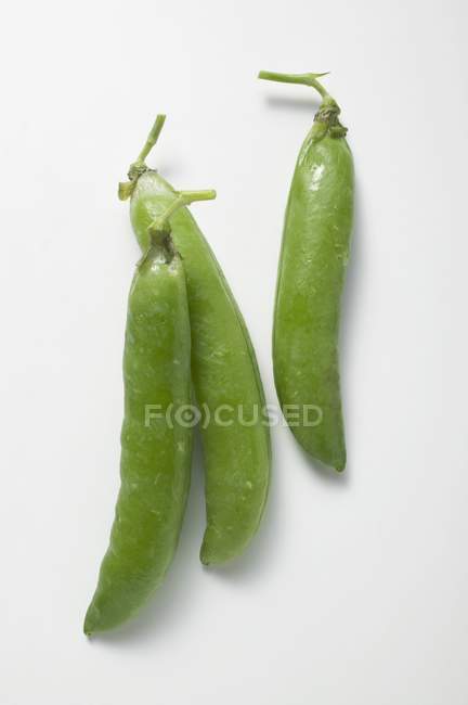 Pea pods on white surface — Stock Photo