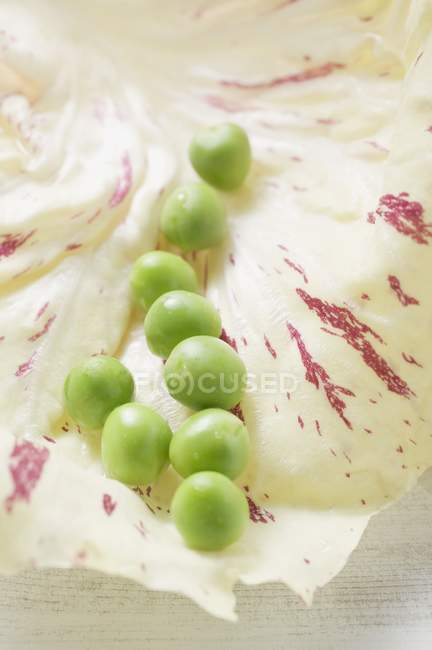Ervilhas frescas na folha de radicchio — Fotografia de Stock