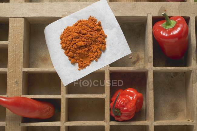 Top view of pepper, chillies and chilli powder in wooden case — Stock Photo