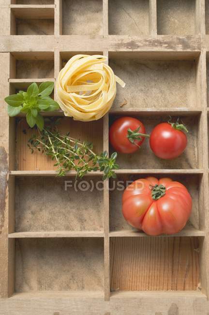 Nido de pasta de cinta cruda y tomates - foto de stock