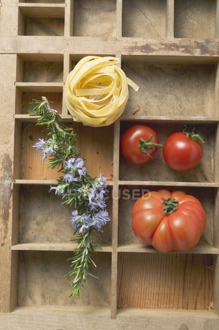 Ninho de macarrão de fita crua e tomates — Fotografia de Stock