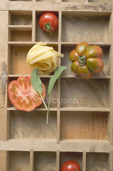 Ninho de macarrão de fita crua e tomates — Fotografia de Stock