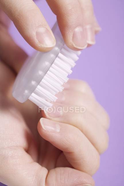 Weibliche Hände schrubben Fingernägel mit Bürste — Stockfoto