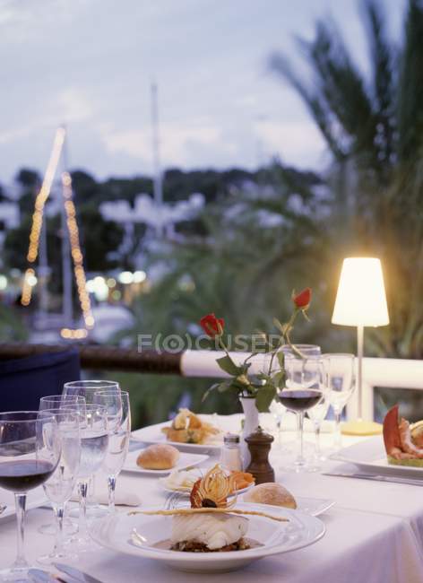 Покладений стіл з морепродуктами, напоями та квітами у вечірньому світлі — стокове фото