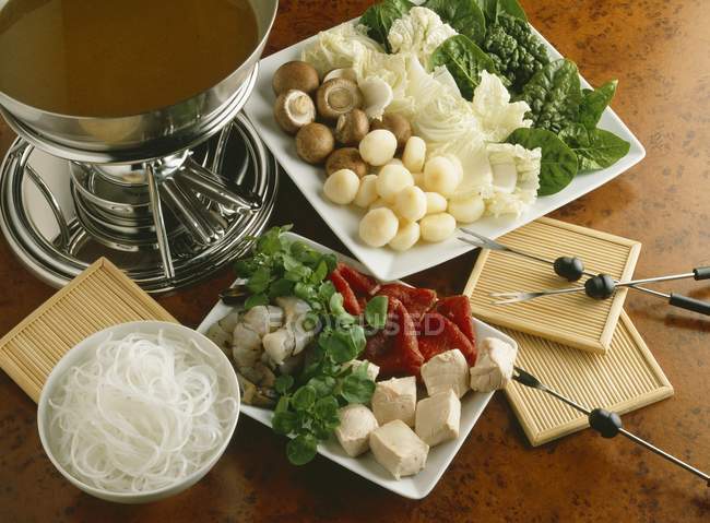 Asian fondue in small plates  over wooden surface — Stock Photo