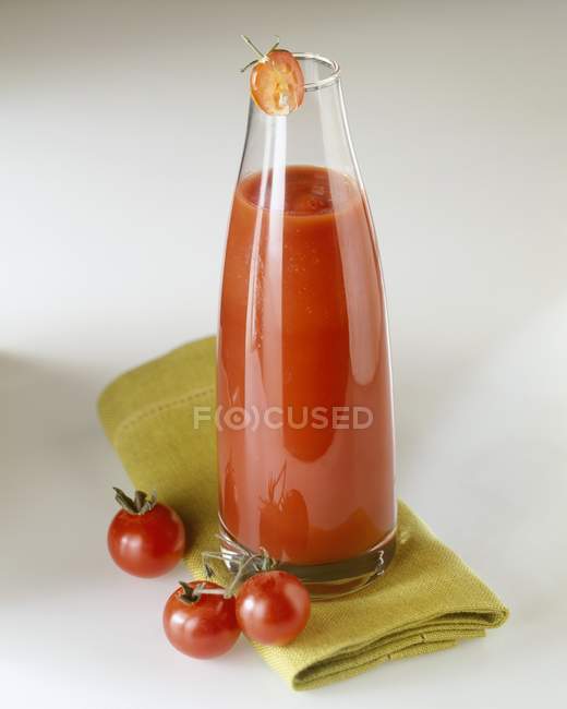 Ketchup de tomate caseiro em garrafa sobre toalha verde na superfície branca — Fotografia de Stock