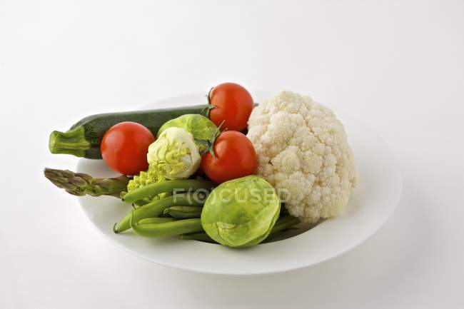 Assorted vegetables on plate over white background — Stock Photo