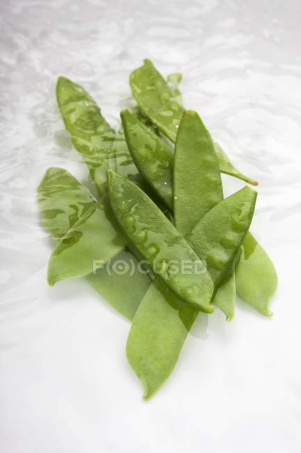 Green Mangetout pods in water — Stock Photo