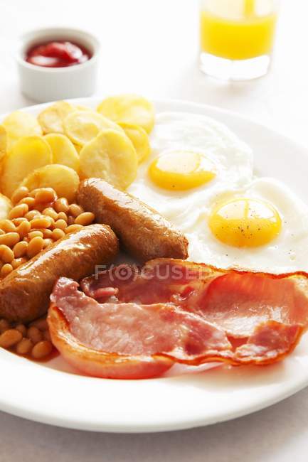 Vista de primer plano del desayuno inglés con zumo de naranja y ketchup - foto de stock