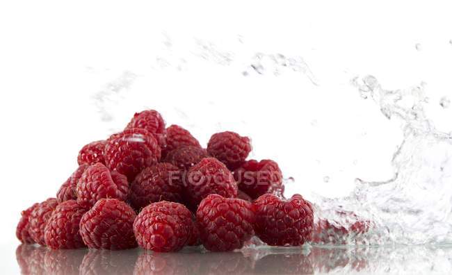 Raspberries with splashing water — Stock Photo