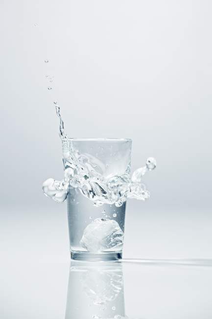 Ледяной куб падает в стакан водки — стоковое фото