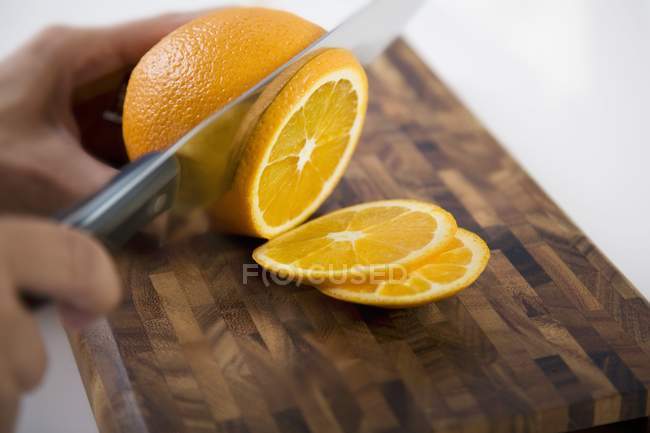 Manos humanas rebanando naranja - foto de stock