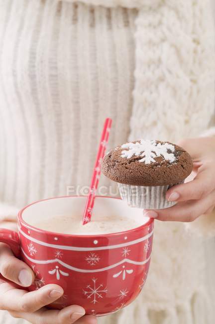 Женщина держит чашку какао и кекс — стоковое фото