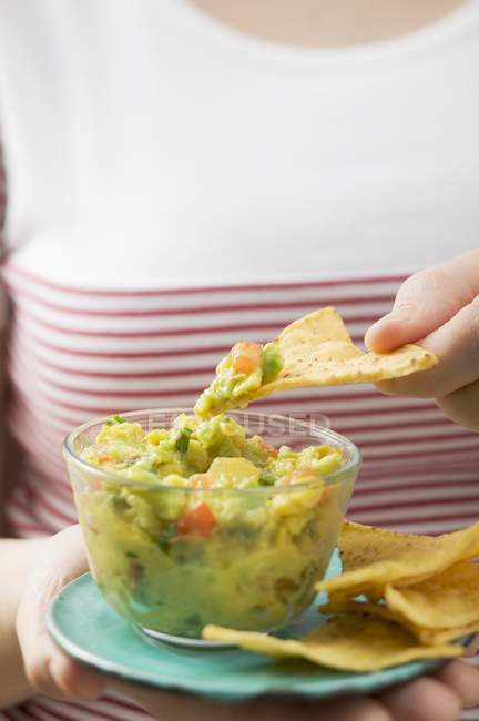 Closeup view of woman dipping Tortilla chip in Guacamole — Stock Photo