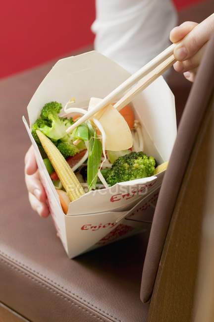 Mulher comendo prato vegetal asiático fora do recipiente take-away — Fotografia de Stock