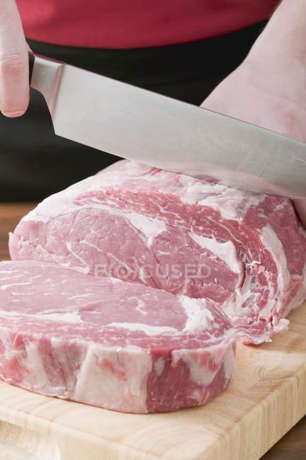 Hombre Rebanando carne cruda - foto de stock