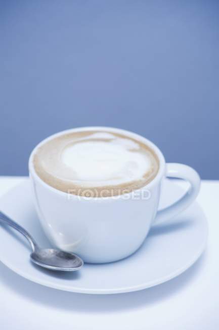 Cappuccino auf dem Teller mit Löffel — Stockfoto