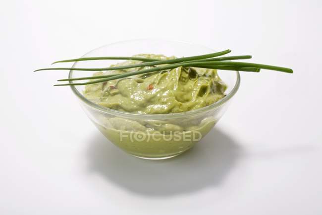 Guacamole in a dish with chives on white background — Stock Photo