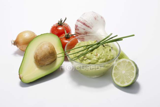 Un plato de guacamole con ingredientes sobre fondo blanco - foto de stock