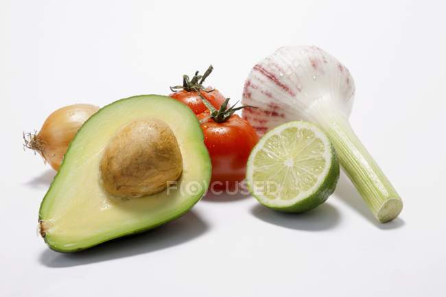 Ingredients for guacamole laying on white surface — Stock Photo