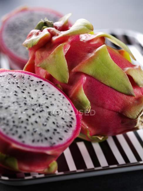 Frutas Pitaya enteras y cortadas a la mitad - foto de stock