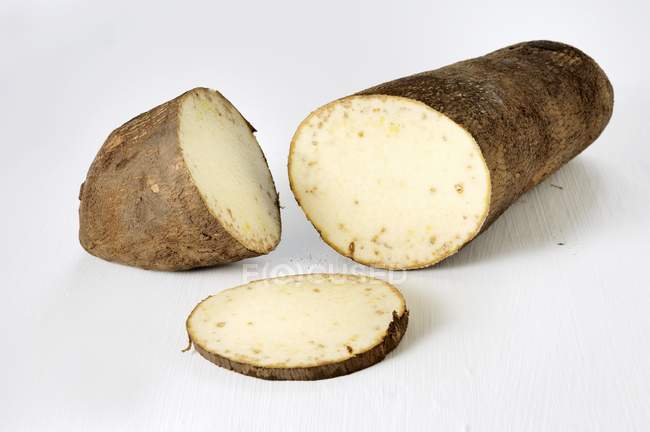 Süßkartoffeln, teilweise in Scheiben geschnitten auf weißer Oberfläche — Stockfoto