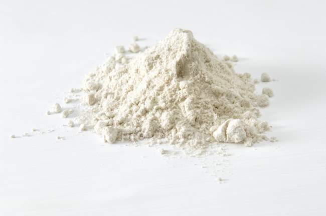 Vista da vicino del mucchio di farina di grano saraceno sulla superficie bianca — Foto stock