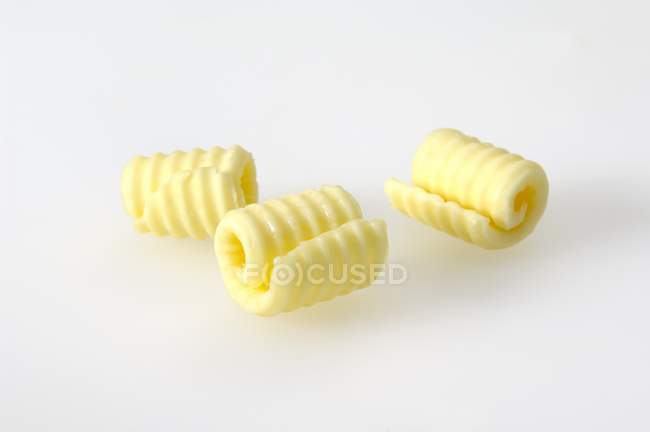 Vista de cerca de tres rizos de mantequilla en la superficie blanca - foto de stock