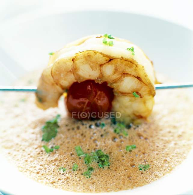 Frothy soup with a prawn and tomato kebab  on white plate — Stock Photo