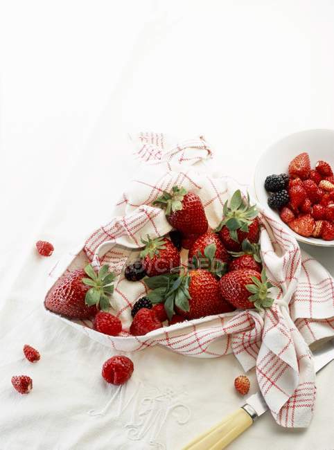 Mixed summer berries in kitchen towel — Stock Photo