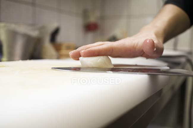 Cropped view of person cutting scallop in half — Stock Photo