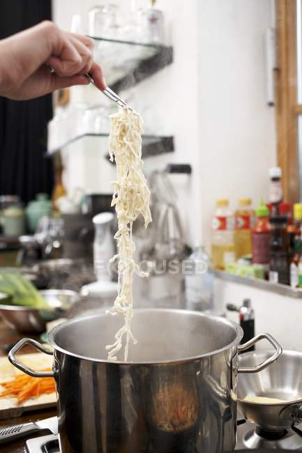 Putting Asian noodles in saucepan — Stock Photo