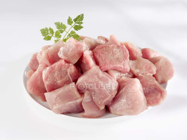 Carne de porco em cubos crus na placa — Fotografia de Stock
