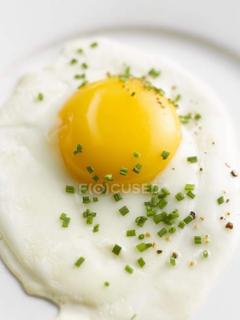 Fried egg with chives and pepper — Stock Photo