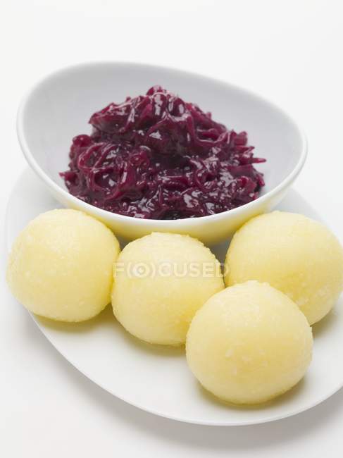 Red cabbage and potato dumplings on white plates over white surface — Stock Photo