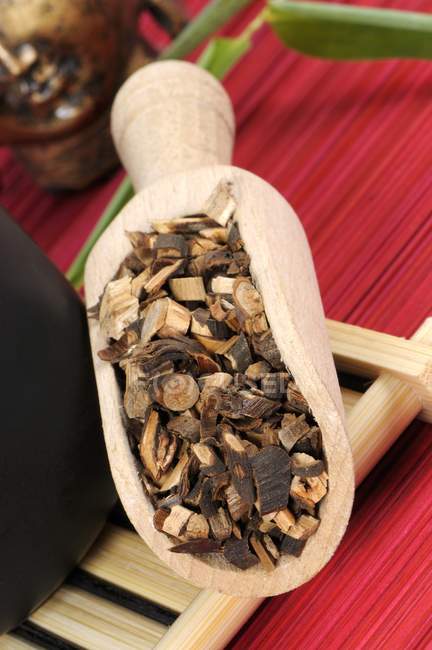 Closeup view of Cassia cinnamon chopped bark in wooden scoop on bamboo tray — Stock Photo