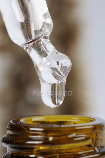 Vista close-up de líquido gotejamento de pipeta para garrafa — Fotografia de Stock