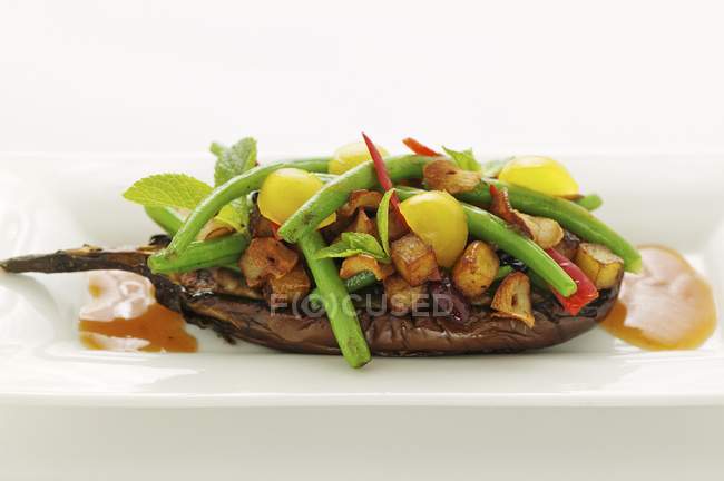 Stuffed aubergines with beans and tamarind sauce on white plate — Stock Photo
