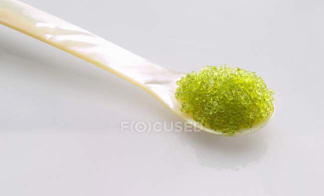 Vista close-up de caviar Masago verde em uma mãe de colher de pérola — Fotografia de Stock