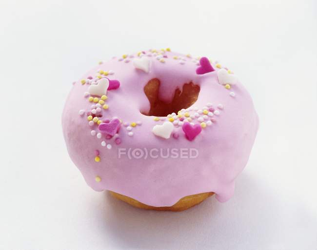Closeup view of one frosted doughnut with pink icing on white surface — Stock Photo