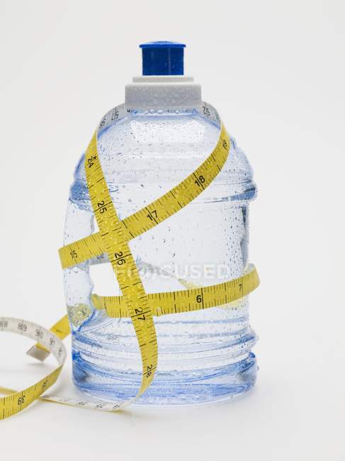Vue rapprochée de la bouteille d'eau en plastique attachée avec du ruban à mesurer — Photo de stock